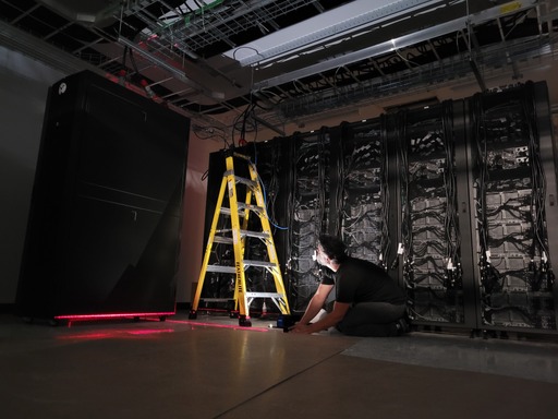 An engineer works with a stepladder on constructing data center racks