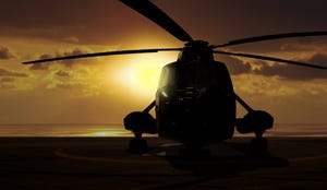 Image shows a military helicopter on carrier ship at sunset.