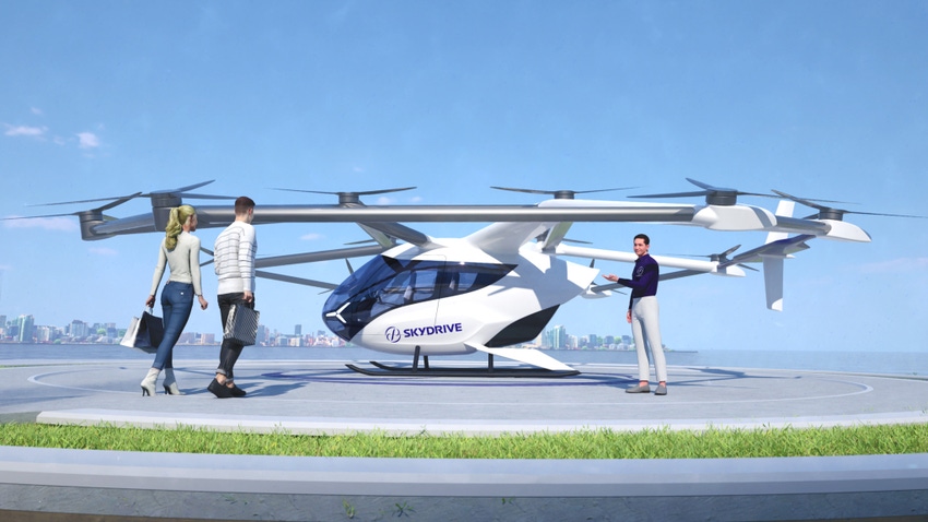 A SkyDrive flying taxi waiting for passengers walking toward it to board.