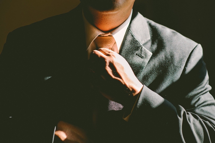 Photo of man in a suit straighening his tie
