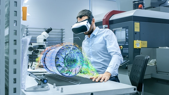 Image shows a factory engineer wearing VR headset designing an engine turbine on a holographic projection table.