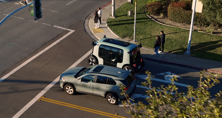 Amazon's Zoox robotaxi sits at a traffic light alongside a regular vehicle. 