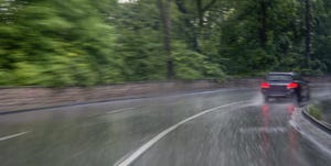 Image shows a car in heavy rain driving through a curve