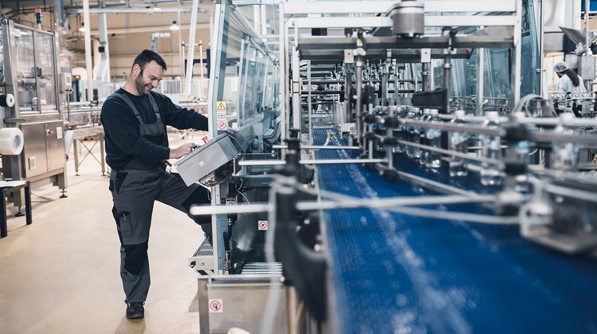 Smiled happy bearded manual worker doing his job on factory production line for water purification and bottling.