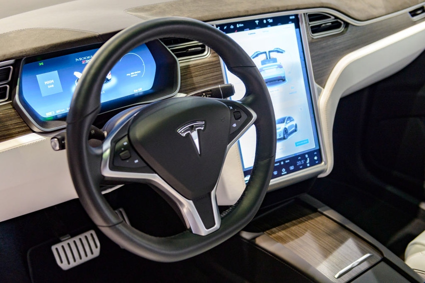 Image shows the inside of a Tesla Model X P90D full electric luxury crossover SUV car with a large touch screen and dashboard