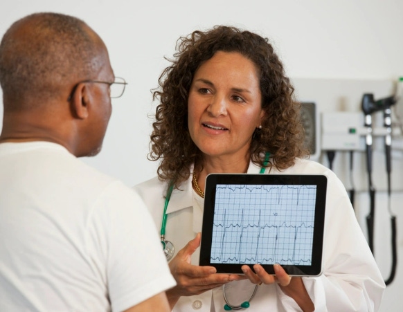 A doctor holding a tablet showing something on the screen to a patient