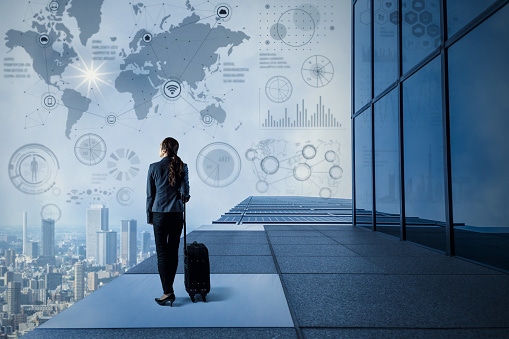 Image shows young business woman standing on rooftop of building.