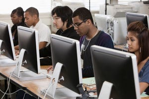 Students learn at a series of computer screens.