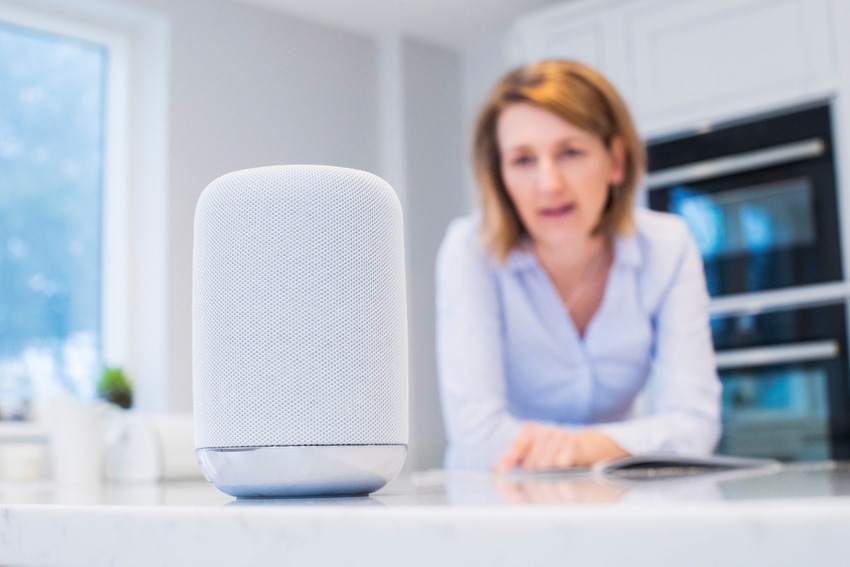 Image shows a woman In Kitchen Asking Digital Assistant Question Image shows a woman In Kitchen Asking Digital Assistant Question