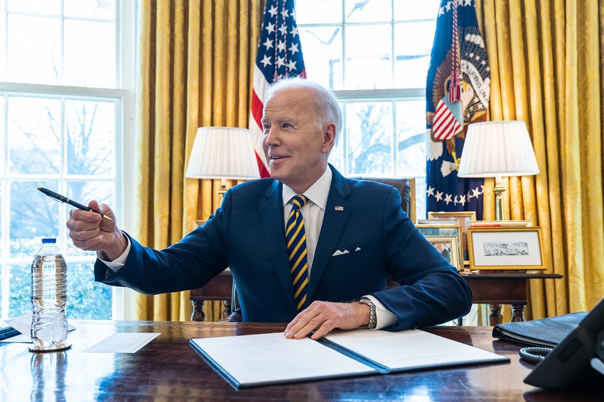 President Joe Biden signing papers in the Oval Office of the White House