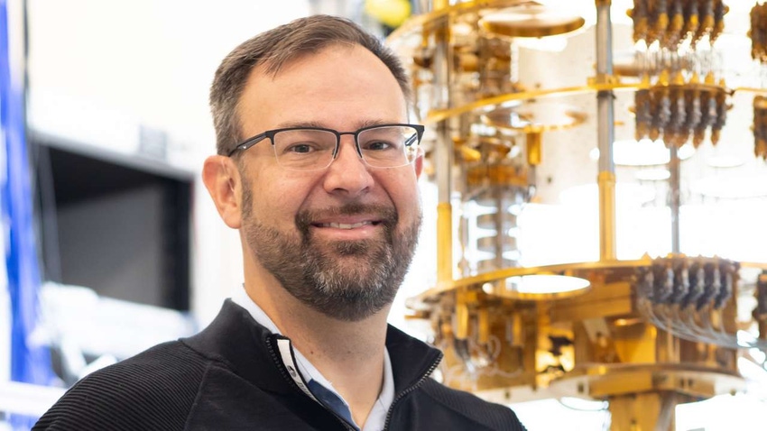 Intel's director of quantum hardware Jim Clarke standing against a quantum computer "chandelier" 
