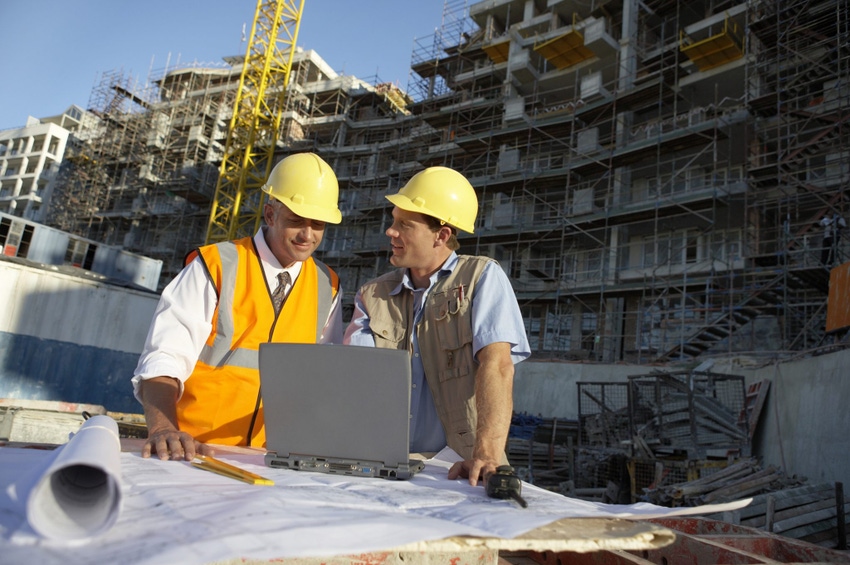 Two Men Wearing Hard Hats Looking at a Laptop Computer on a Building Site Two Men Wearing Hard Hats Looking at a Laptop Computer on a Building Site