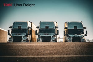Three Uber Freight trucks lined up in a row.