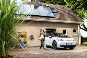 A home exterior with solar panels and an electric car charging.