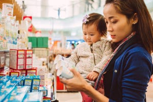 Image shows Young mom shopping for groceries / medicine with toddler shopping