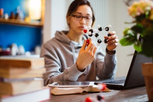 A woman researcher examines a model of a molecule