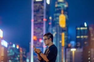 A man uses a smartphone in a city at night