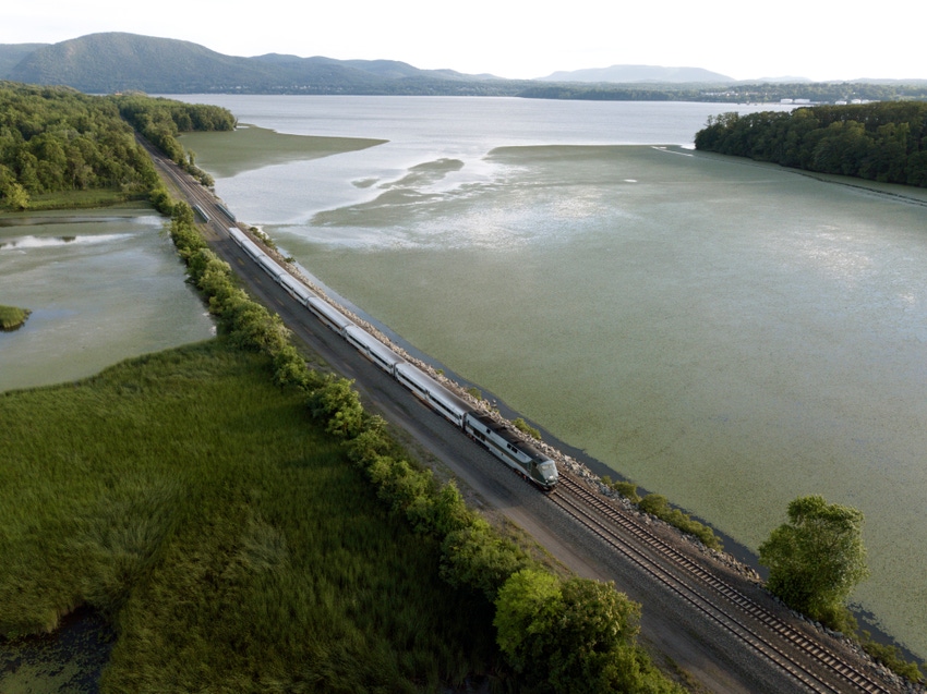 Image shows a passenger train traveling up the hudson river Image shows a passenger train traveling up the hudson river