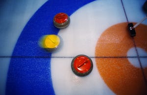 Image shows curling stones moving over ice
