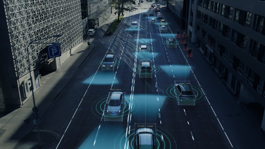 Image shows an aerial drone shot of autonomous self-driving cars moving through a city.