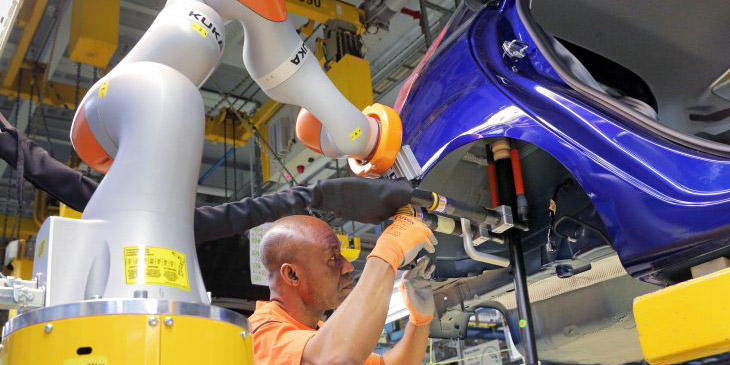Robots and people work side by side in a Ford plant.