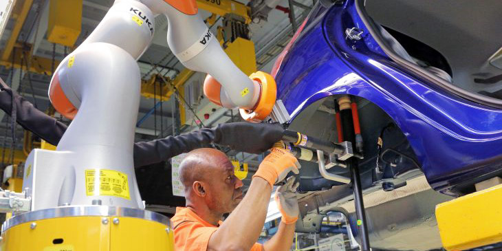 Robots and people work side by side in a Ford plant. Robots and people work side by side in a Ford plant.