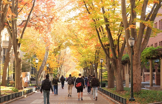 Image shows a university campus with students walking.