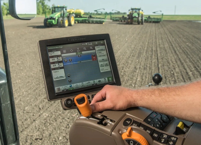 Image shows a farmer using data viewed on a screen inside equipment while out in the field.