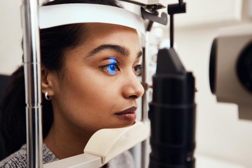 A woman has her eye scanned by an optometrist.