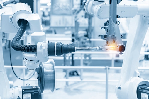 Image shows a robotics arm welding automotive parts.