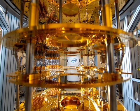 An Intel quantum computer in a golden chandelier configuration with the Intel logo on the wall behind it