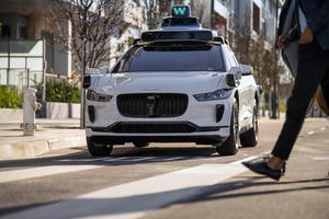 A white Waymo i-Pace driverless taxi on a road. 