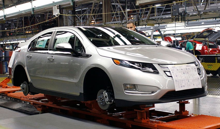 Image shows assembly line workers assemble Chevy Volt electric vehicles and Opel Amperas at the General Motors Detroit Hamtra