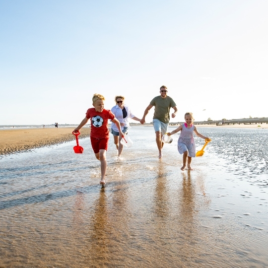 Family running on beach in Kent