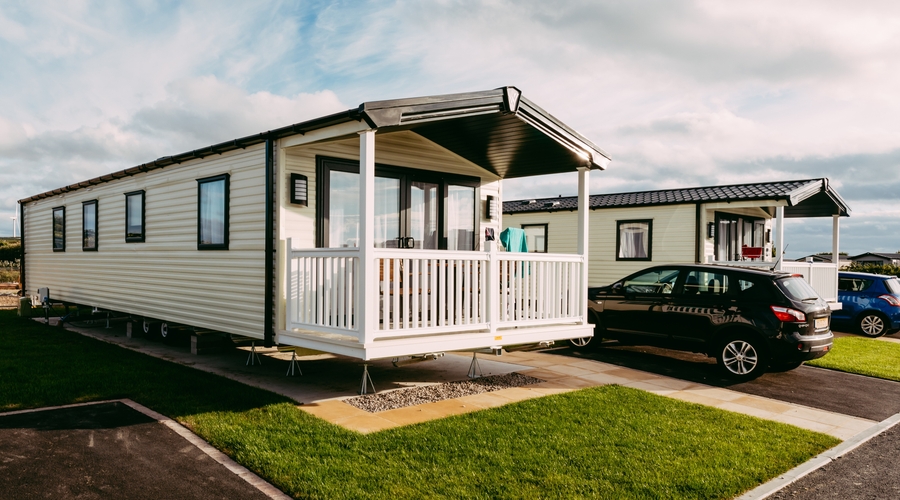 static caravan with decking and black car parked next to it on Pentire Holiday Park in Cornwall