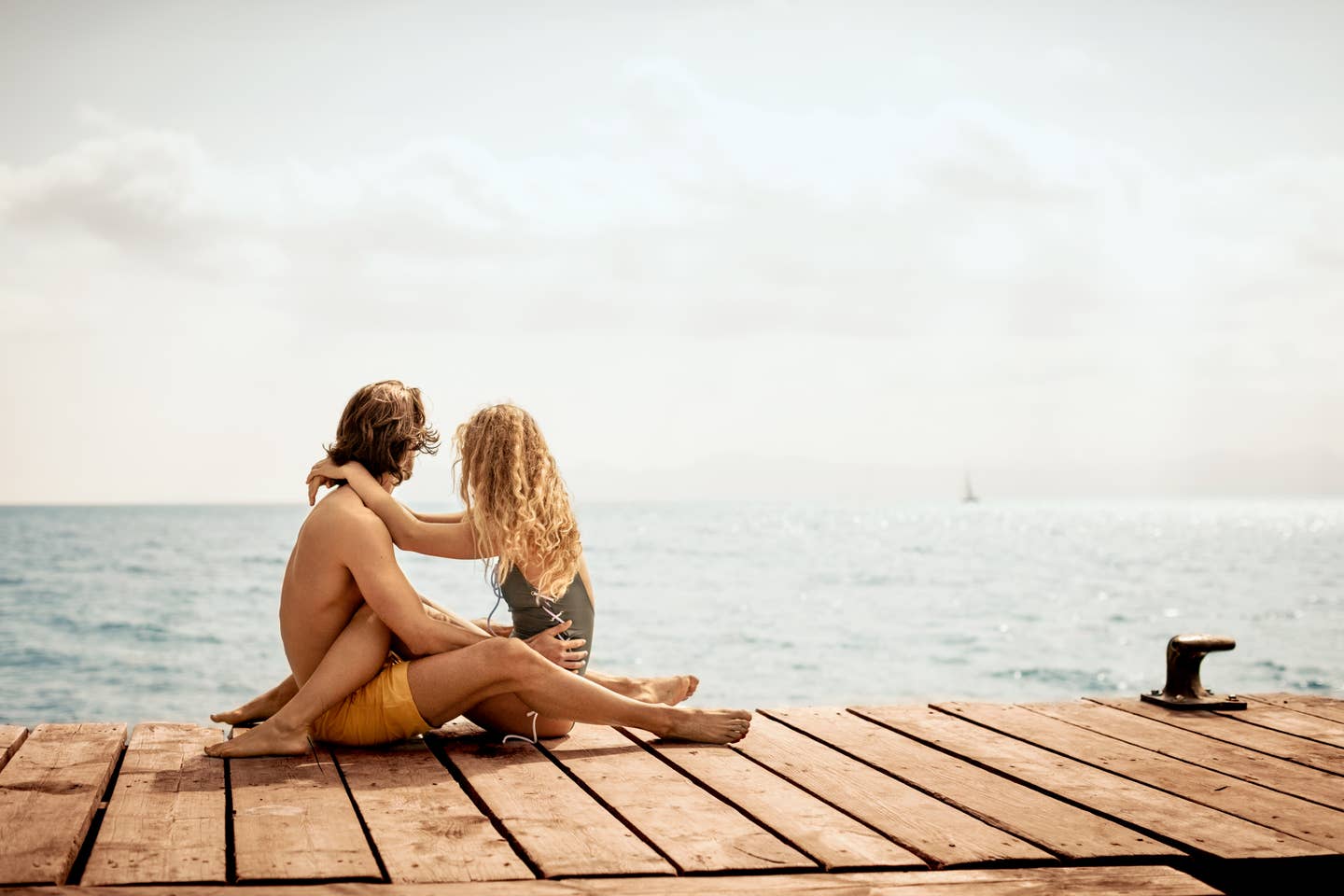 Ein Paar, welches auf einem Steg am Meer sitz und sich umarmt. Ein Paar, welches auf einem Steg am Meer sitz und sich umarmt.