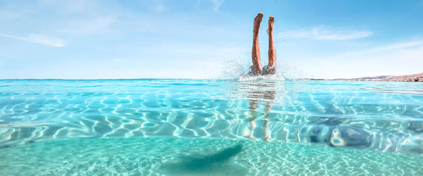 Jemand, der Handstand im türkisblauen Meer macht.