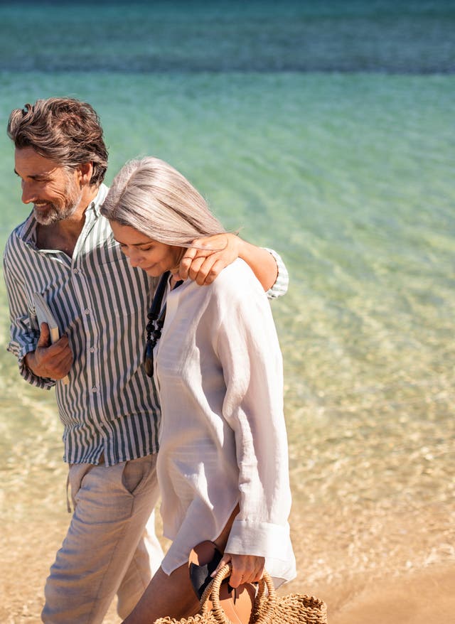 Beliebte Reiseziele Paar, das Arm in Arm am Strand läuft