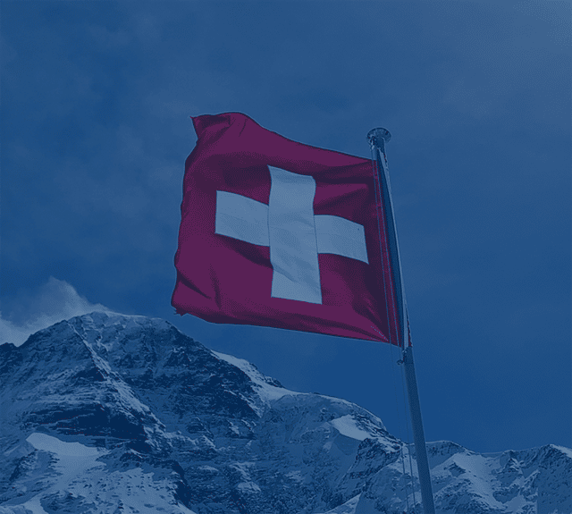 Stand in der Schweiz Man sieht eine Schweizer Flagge sowie Berge im Hintergrund.