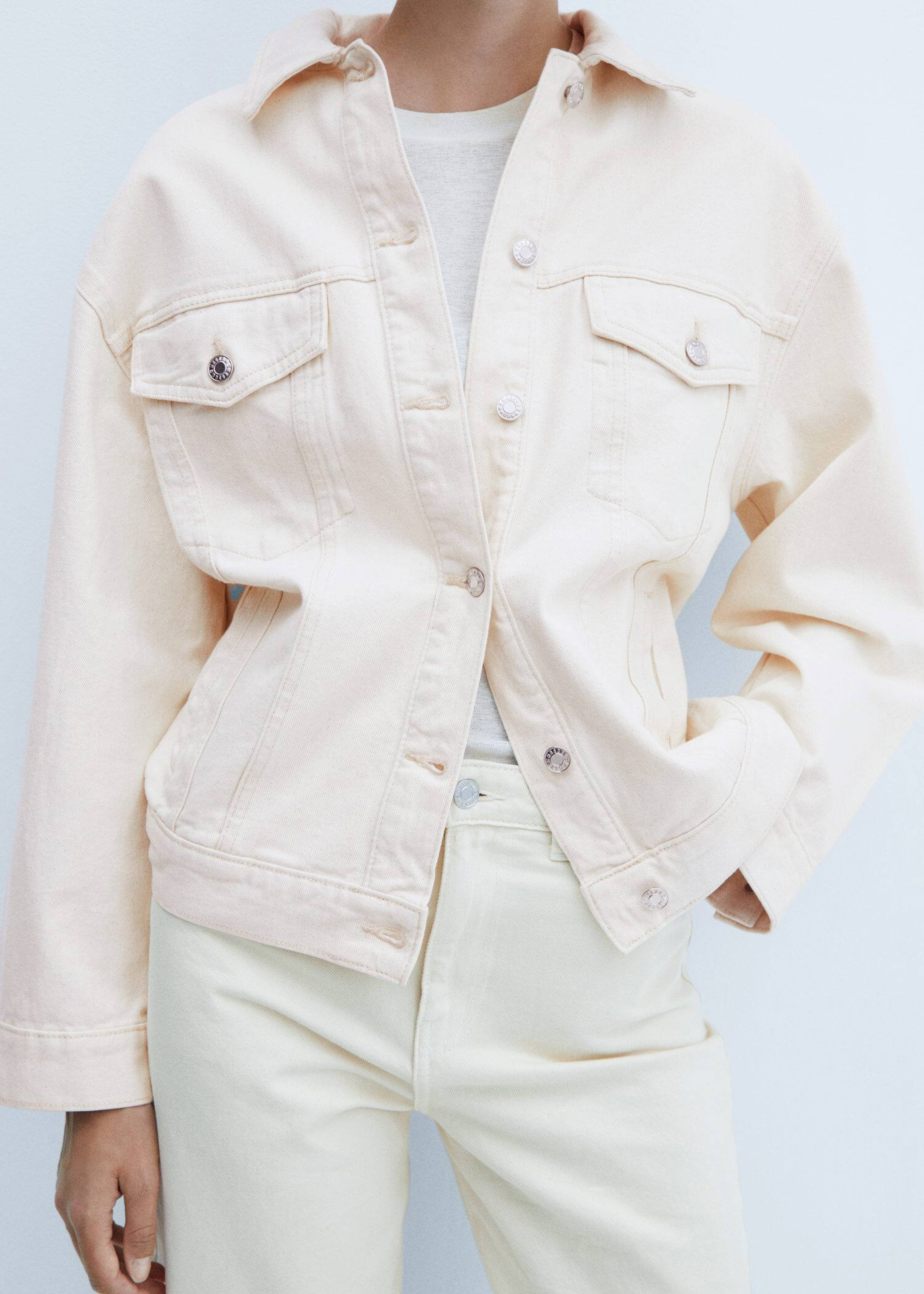 A woman combining jeans with a beige jacket.