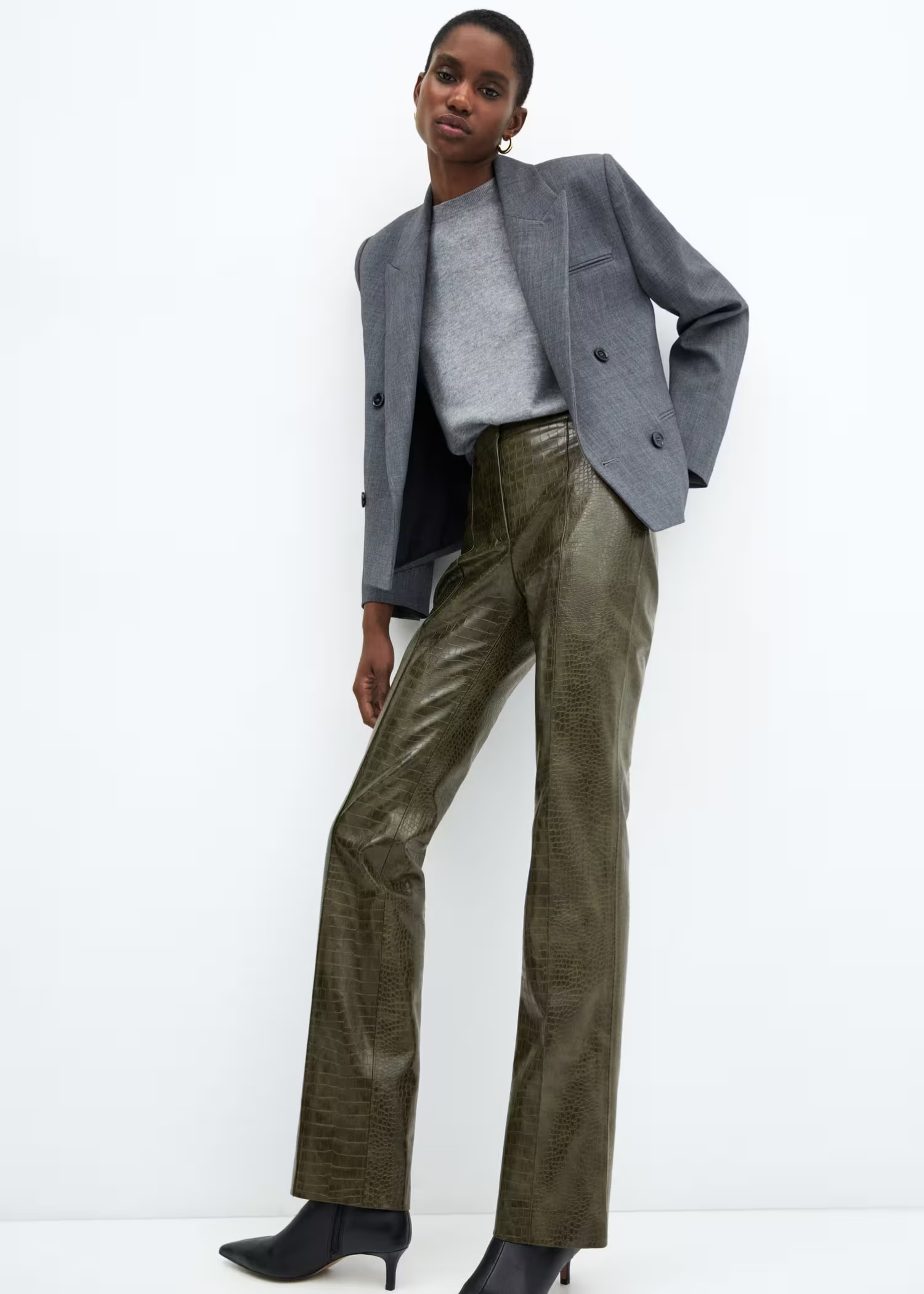 Woman wearing a grey blazer and leather trousers.