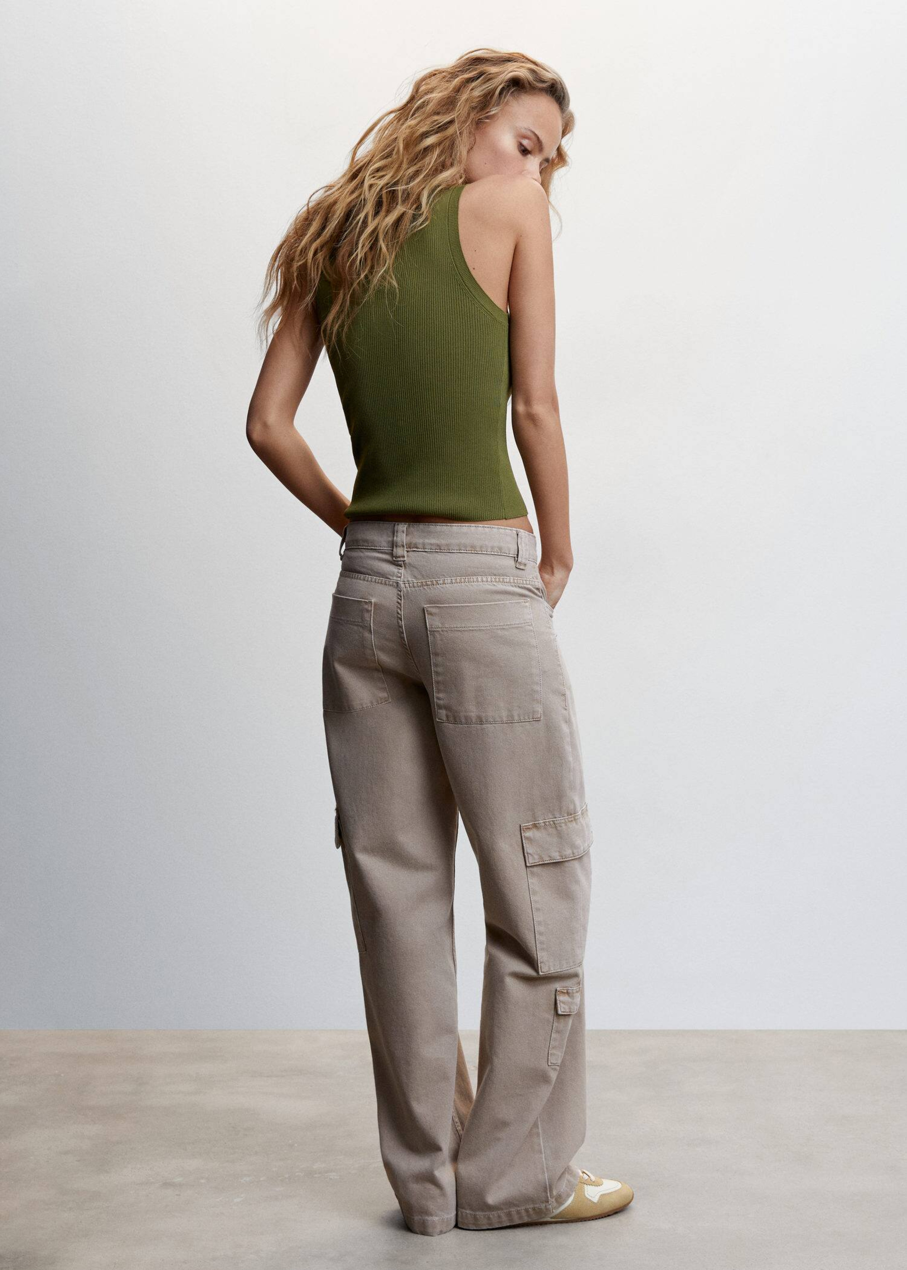 Mujer combinando pantalones cargo beige con un top verde.