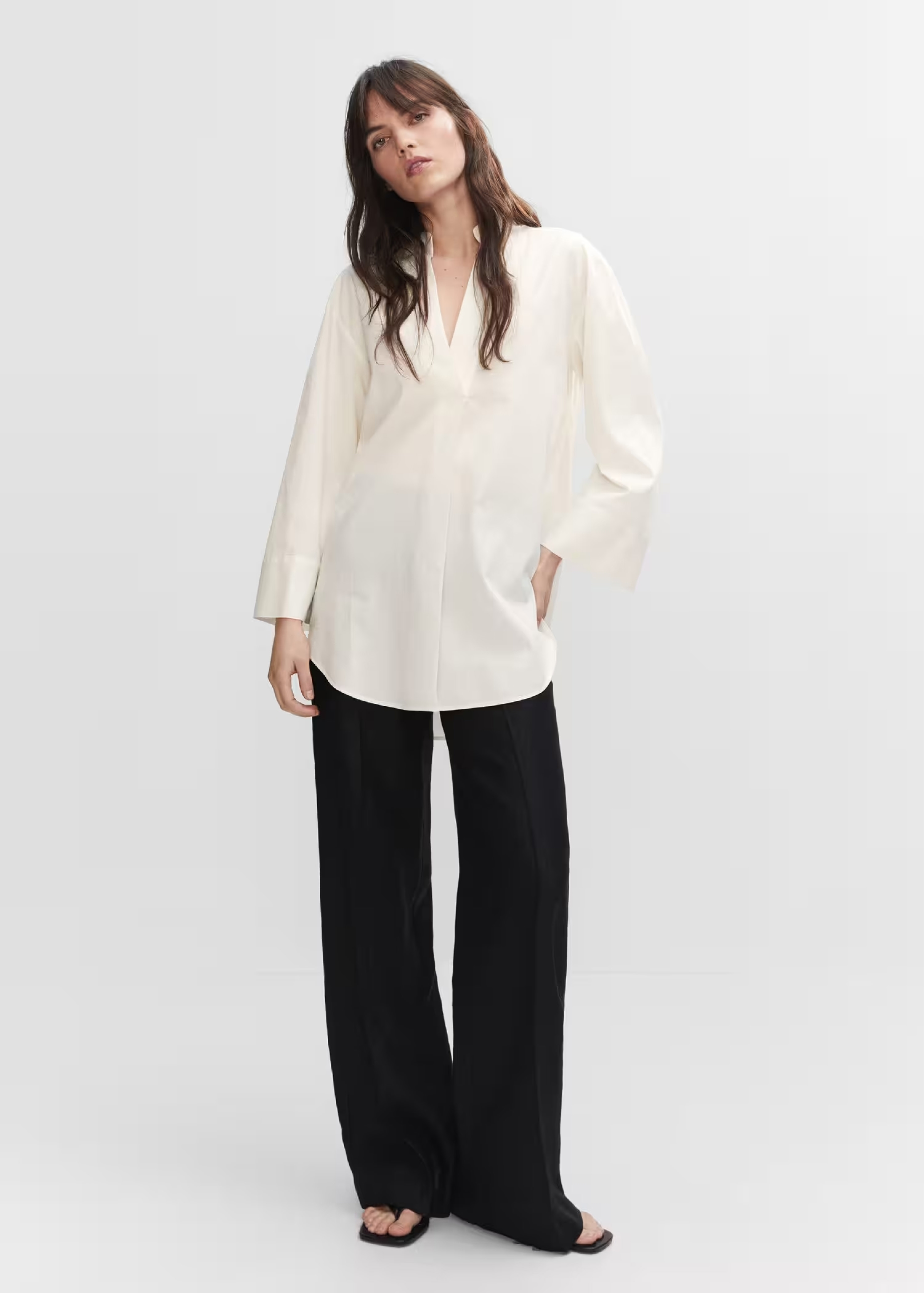 Woman wearing an oversize look with a white shirt and basic black trousers.