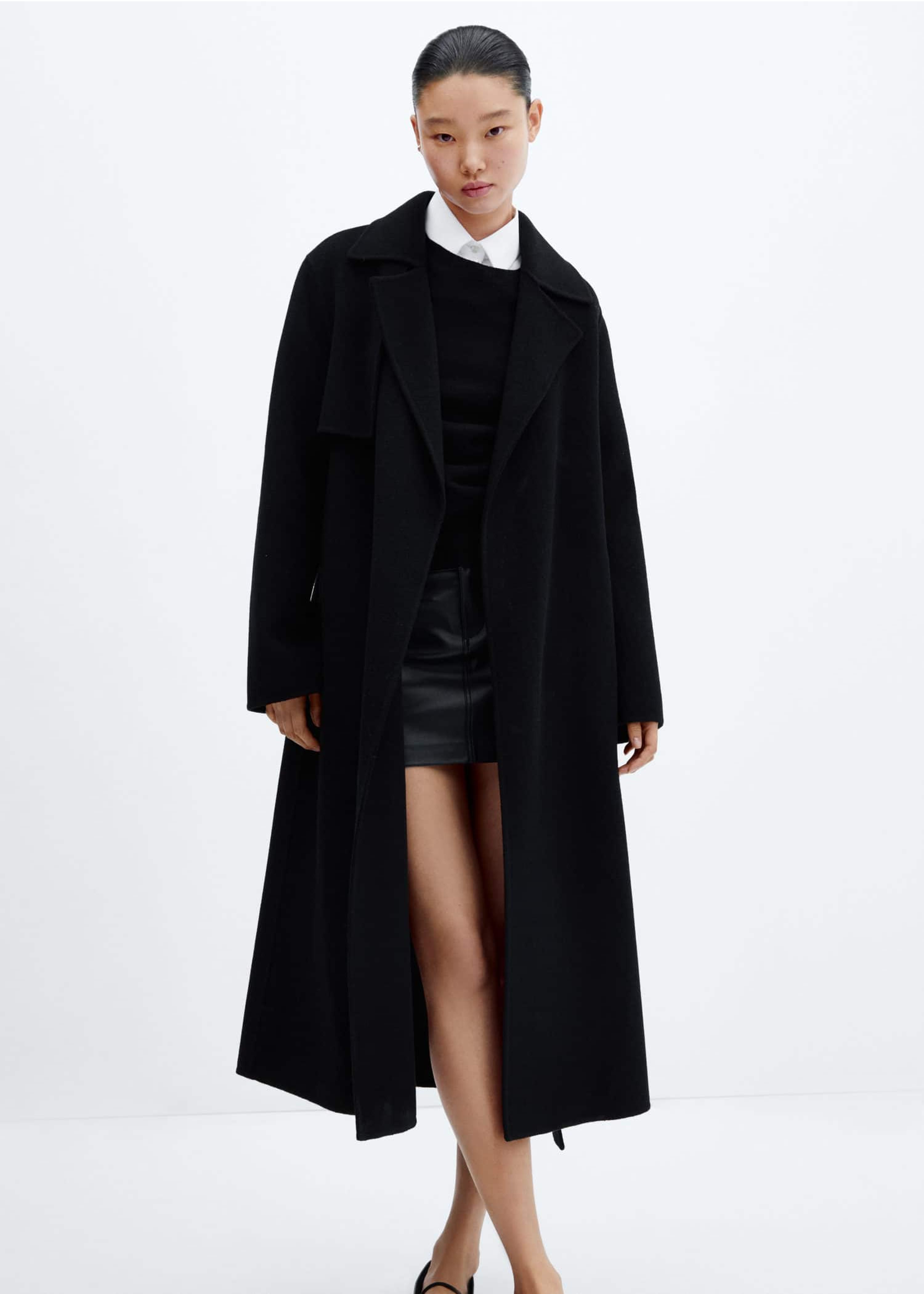 Mujer vestida con un vestido corto y un abrigo largo negro