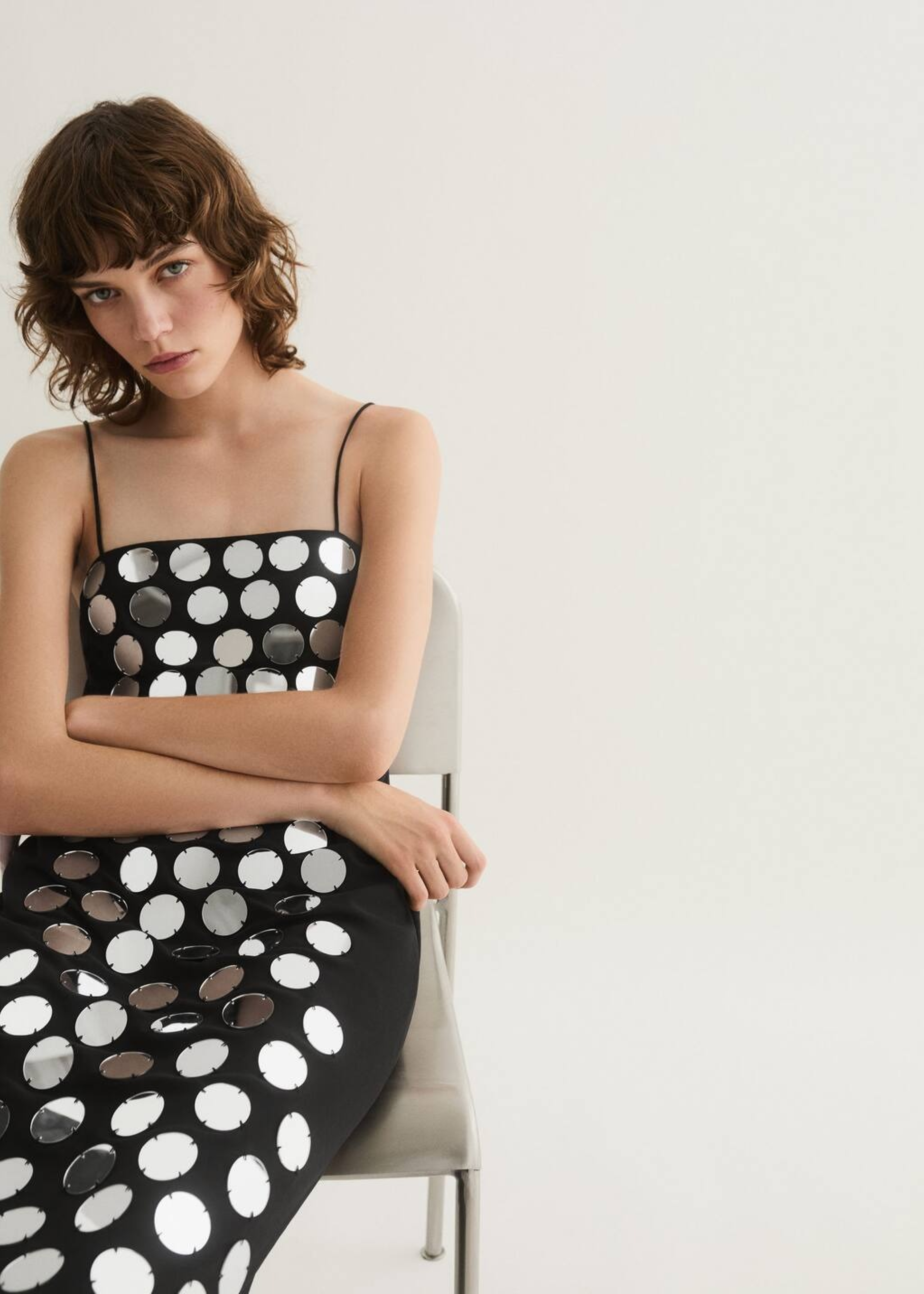 Un look con un abito nero con specchi.