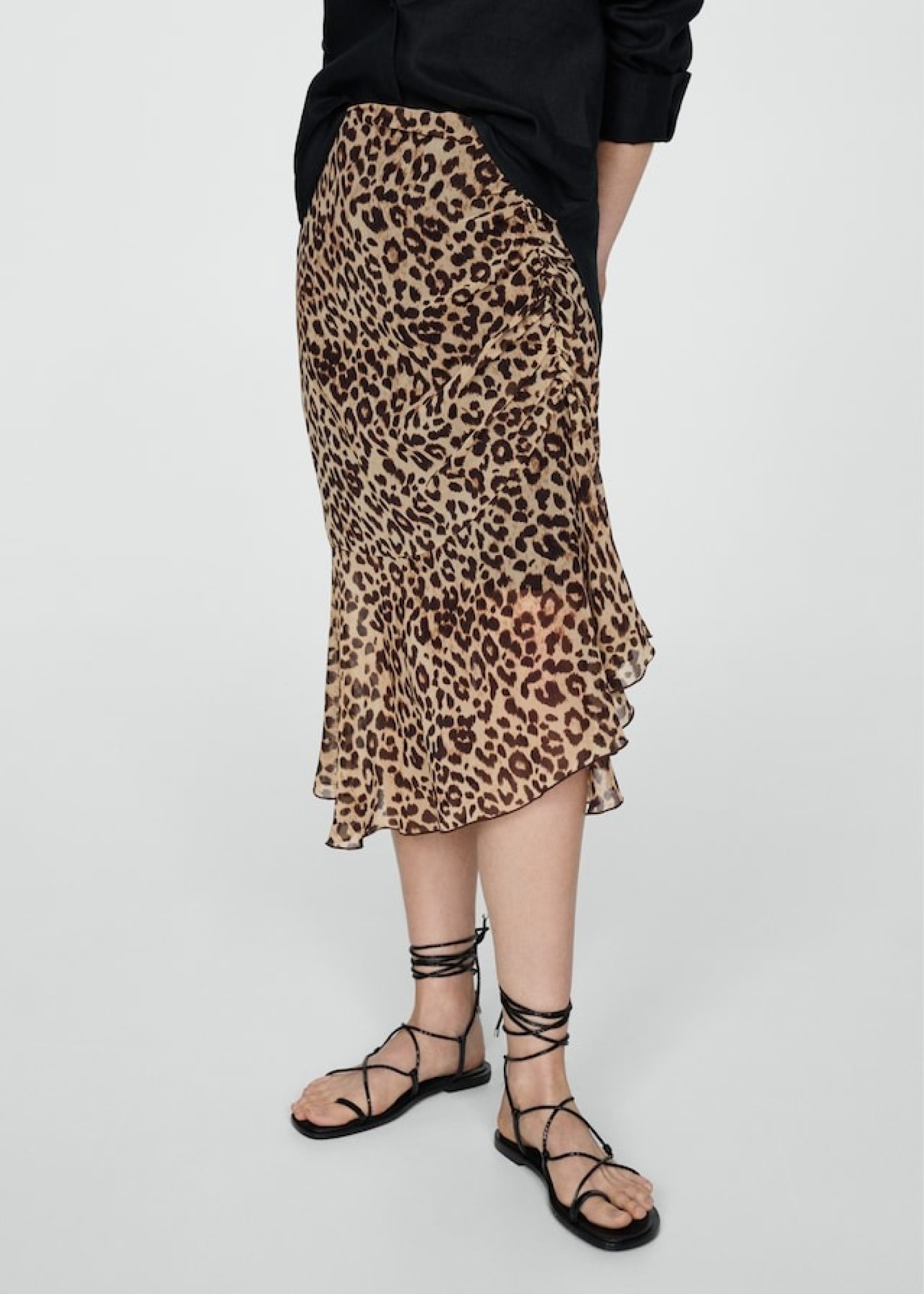 Woman combining an animal print skirt with sandals and a black blouse.