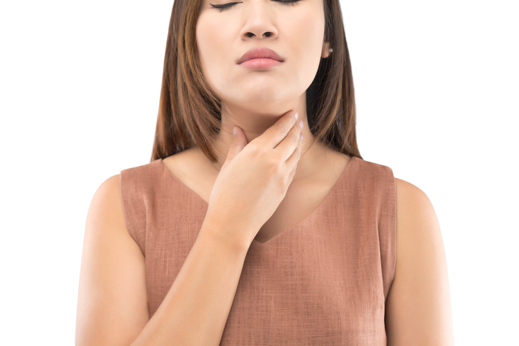 a woman feeling sore throat and touching her throat in discomfort