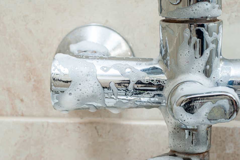 A hand cleaning the bathroom taps