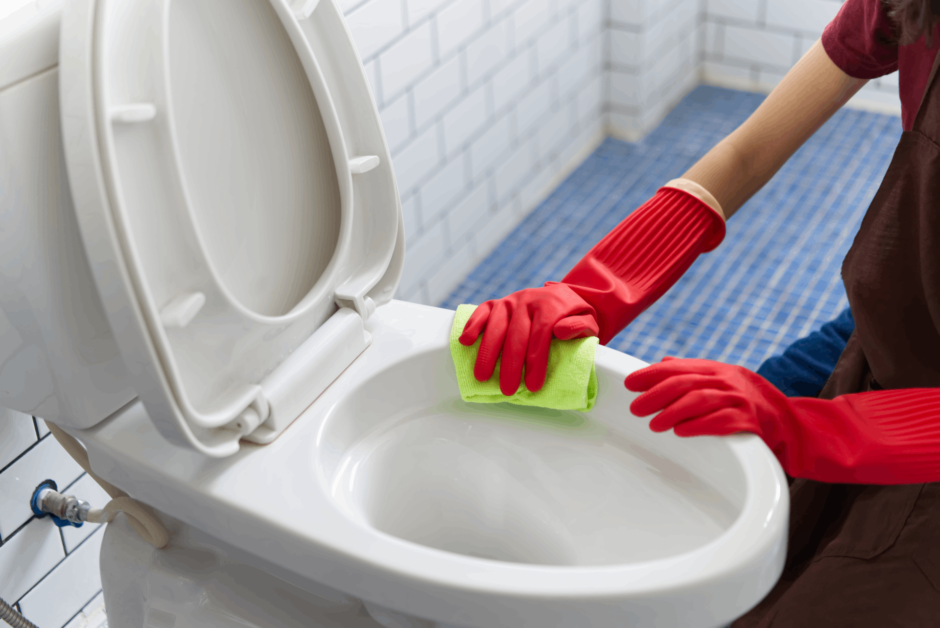Mujer lavando el inodoro con guantes rojos
