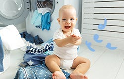 Mosolygó kisbaba a mosogatógép előtt